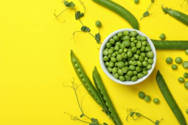 Sarı zemin üzerinde taze bezelye tohumları olan bir kase.