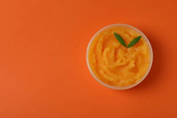 Cosmetic skin care scrub on orange background