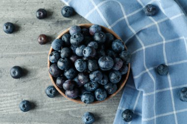 Gri desenli arka planda bir kase taze yaban mersini.