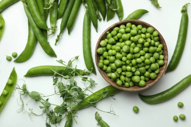 Bowl with pea seeds and fresh pea on white background