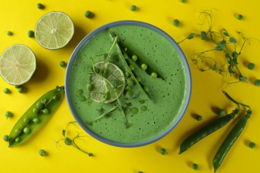 Sarı zemin üzerinde bezelye çorbası ve malzeme tabağı.