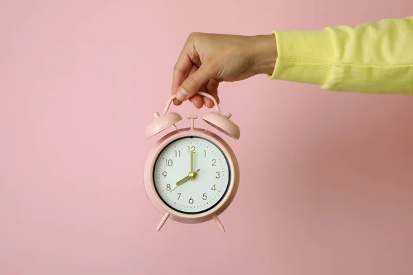 Mano Femenina Sostiene Despertador Sobre Fondo Rosa —  Fotos de Stock