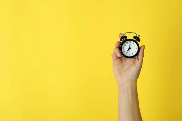 Female Hand Holds Alarm Clock Yellow Background — Stockfoto