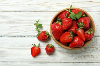 Beyaz ahşap arka planda bir kase çilek