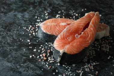 Siyah dumanlı arka planda taze çiğ somon ve tuz.