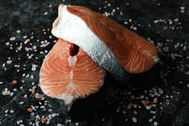 Siyah dumanlı arka planda taze çiğ somon ve tuz.
