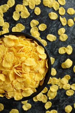 Bir kase mısır gevreği ve siyah dumanlı arka planda serpiştirilmiş mısır gevreği.