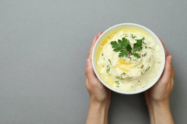 Kadın eli, arka planda bir kase patates püresi tutuyor.