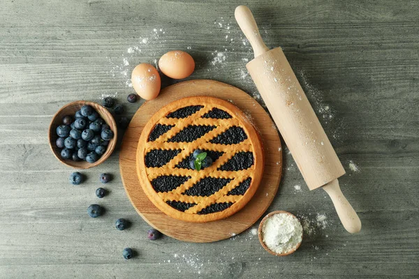 Concept of cooking blueberry pie on gray textured background
