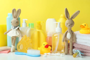Sarı arka planda farklı bebek hijyeni aksesuarları.