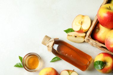 Homemade apple vinegar and ingredients on white textured table