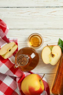 Homemade apple vinegar and ingredients on white wooden table