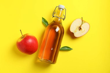 Ev yapımı elma sirkesi ve sarı arka planda malzemeler.