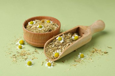 Yeşil arka planda kurumuş papatya çayıyla kepçe ve kase.