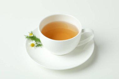 Beyaz arka planda bir fincan papatya çayı.