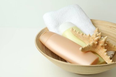 Beyaz arka planda saç bakım aksesuarları olan bir kase.