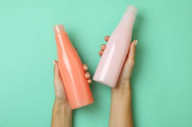 Kadın elleri arka planda boş şampuan şişeleri tutuyor.