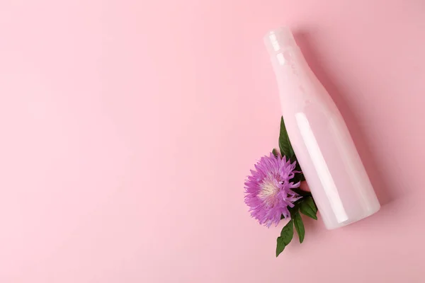 ピンクの背景にシャンプーと花のブランクボトル — ストック写真