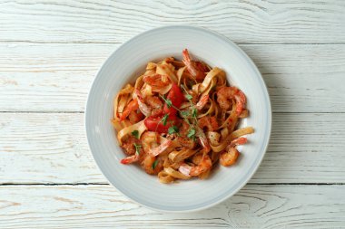 Beyaz ahşap zemin üzerinde bir tabak karides makarna.