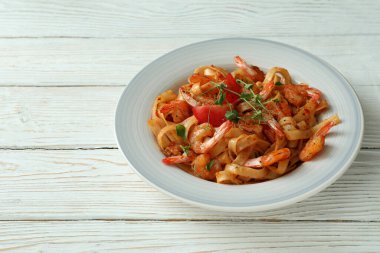 Beyaz ahşap zemin üzerinde bir tabak karides makarna.