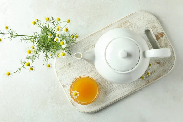 Concept of breakfast with chamomile tea on white textured table