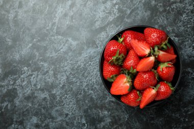 Siyah dumanlı arka planda bir kase taze çilek.