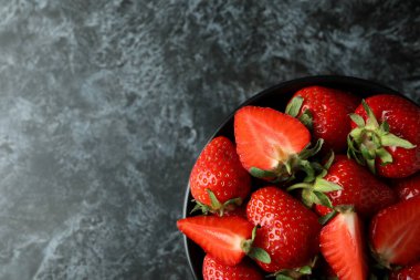 Siyah dumanlı arka planda bir kase taze çilek.