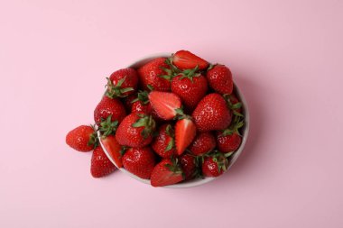 Pembe arka planda bir kase taze çilek