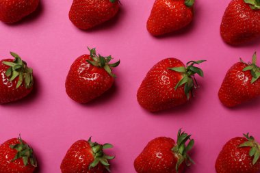 Pembe arka planda yaprakları olan taze, lezzetli bir çilek.