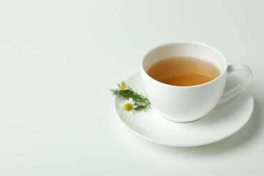 Beyaz arka planda bir fincan papatya çayı.