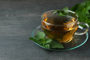 Koyu ahşap masada bir fincan ısırgan otu çayı