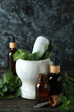 Taze ısırgan otu ve ahşap masada gerekli yağlarla havan topu.