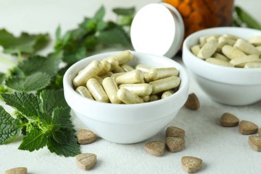 Isırgan otu hapları ve malzemeler beyaz desenli masada.