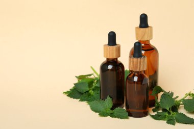 Bej arka planda ısırgan otu özü yağı şişeleri