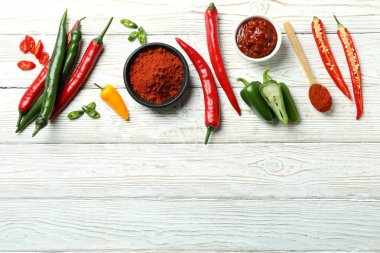 Beyaz ahşap arka planda acı biber, sos ve toz.