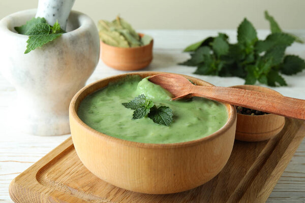 Concept of healthy food with nettle soup on white wooden table