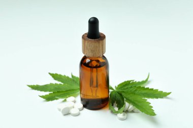 Beyaz arka planda esrar yaprakları, haplar ve yağ