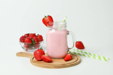 Cam kavanoz çilekli milkshake ve malzemeler beyaz masada.