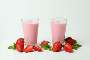 Çilekli milkshake bardakları ve beyaz arka plandaki malzemeler.