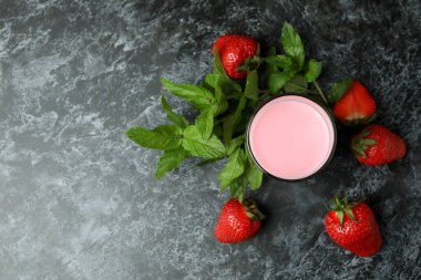 Cam kavanoz çilekli milkshake ve siyah dumanlı masa malzemeleri.