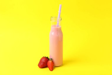 Sarı arka planda bir şişe çilekli milkshake.