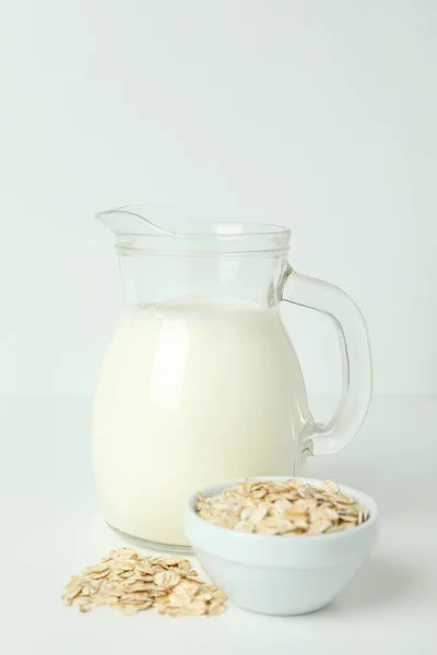 Pitcher of milk and cereals on white background