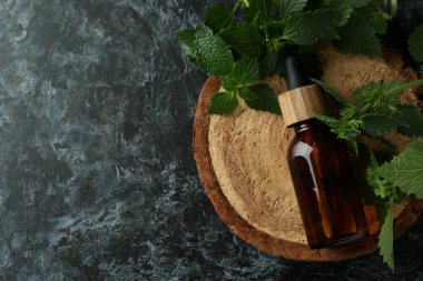 Siyah duman masasında bir şişe ısırgan otu özü yağı.