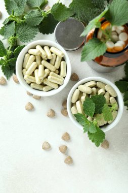 Isırgan otu hapları ve malzemeler beyaz desenli masada.