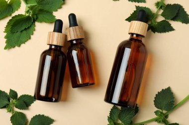 Bej arka planda ısırgan otu özü yağı şişeleri