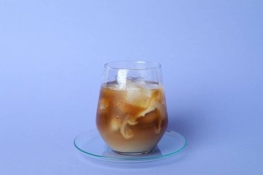 Mor arka planda bir bardak buzlu kahve.