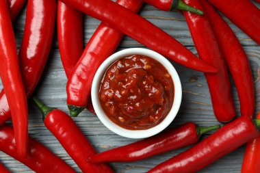 Kırmızı biber ve gri ahşap arka planda sos.