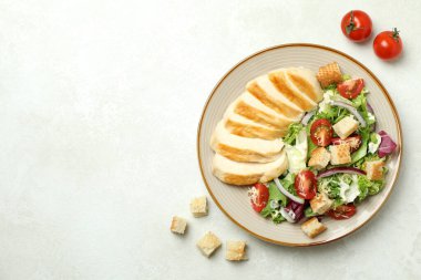 Sezar salatası ve beyaz desenli arka plandaki malzemelerle dolu bir tabak.