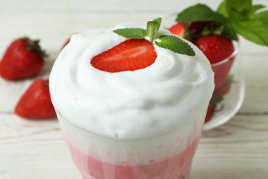 Bir bardak çilekli milkshake ve beyaz ahşap masa malzemeleri.