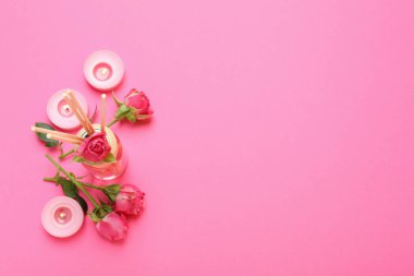 Diffuser, candles and roses on pink background